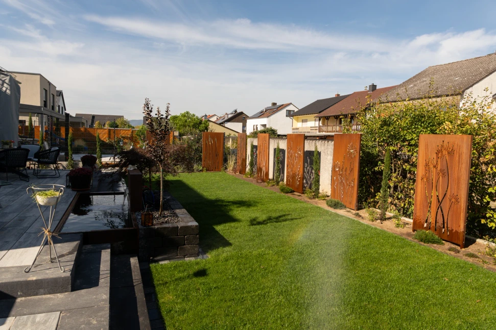 Terrasse mit Gartenbrunnen, Rasen und bepflanzten Randbereichen in Haßloch
