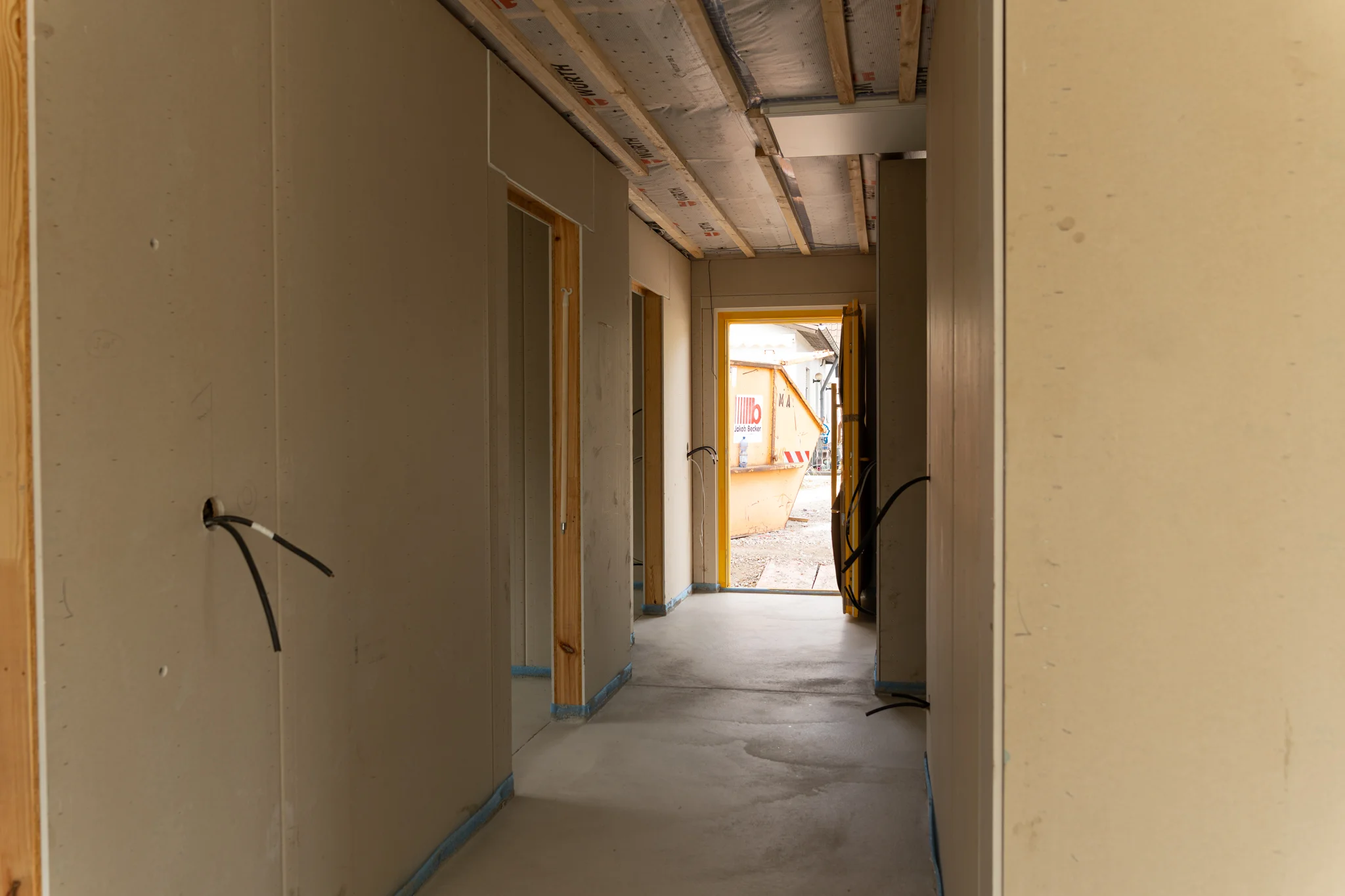 Flur im Ausbau mit offenen Türdurchgängen und Blick zur Haustür