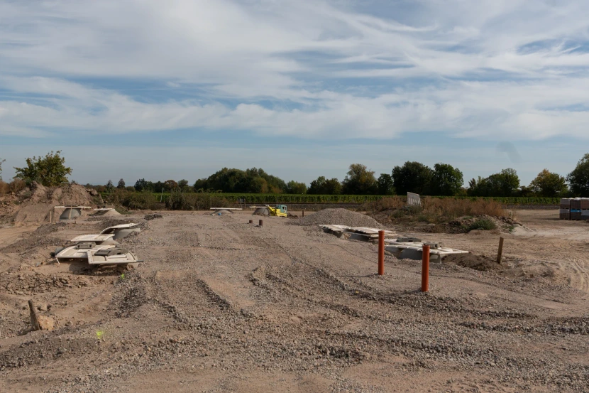 Gravel surface with covered access chambers and orange pipes at the development site